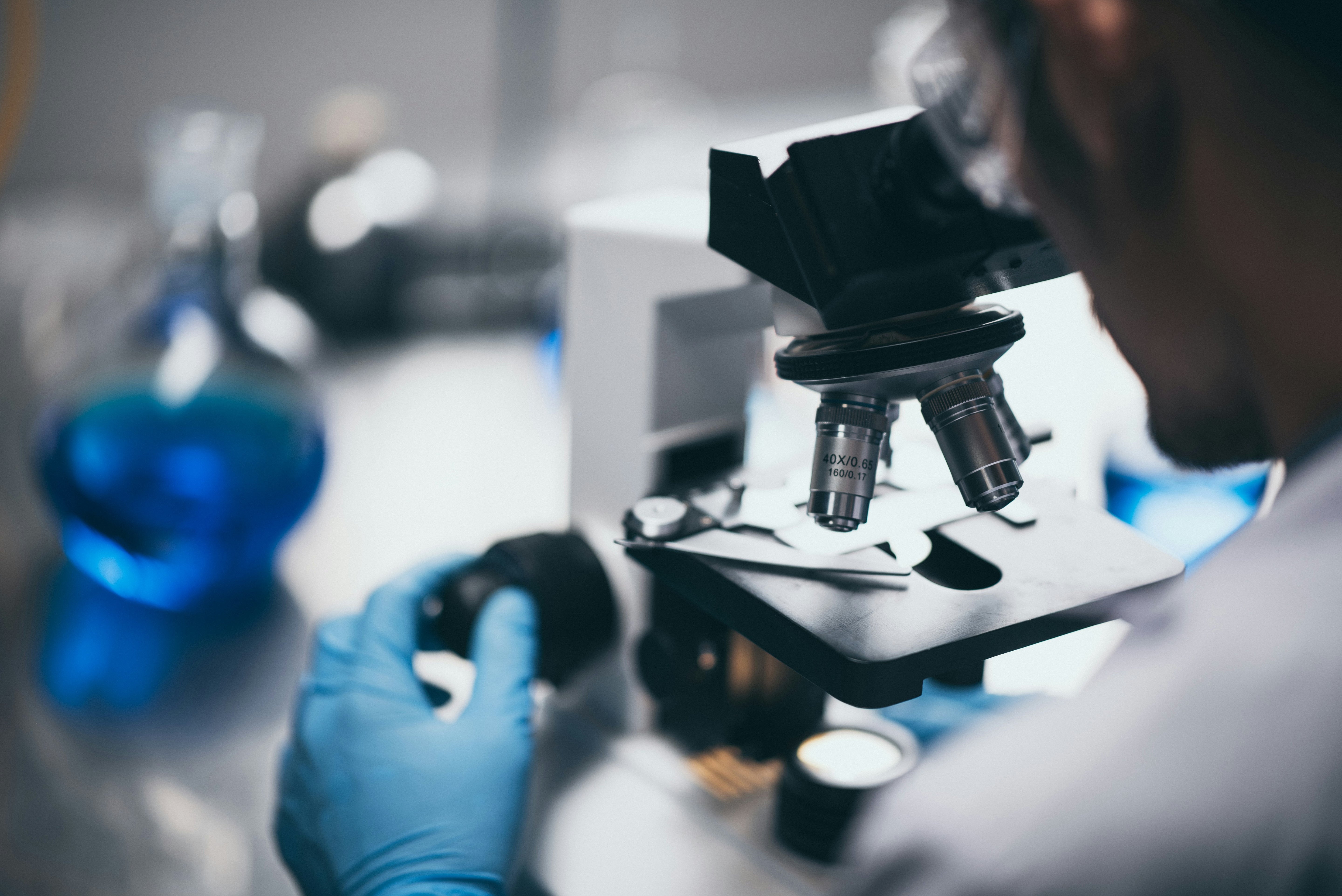 Person using a microscope in a laboratory setting with gloves on